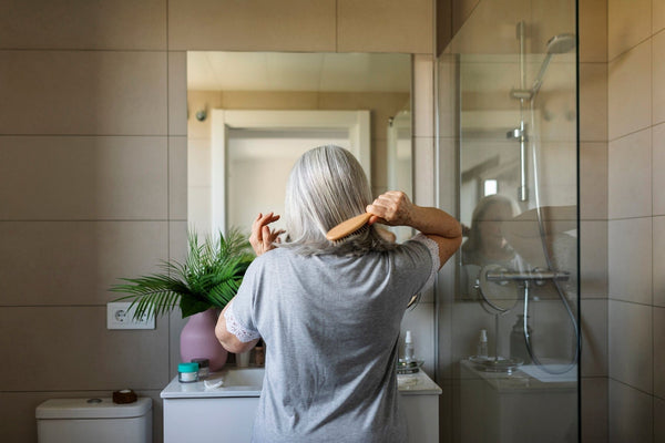 Woman brushing her hair in bathroom