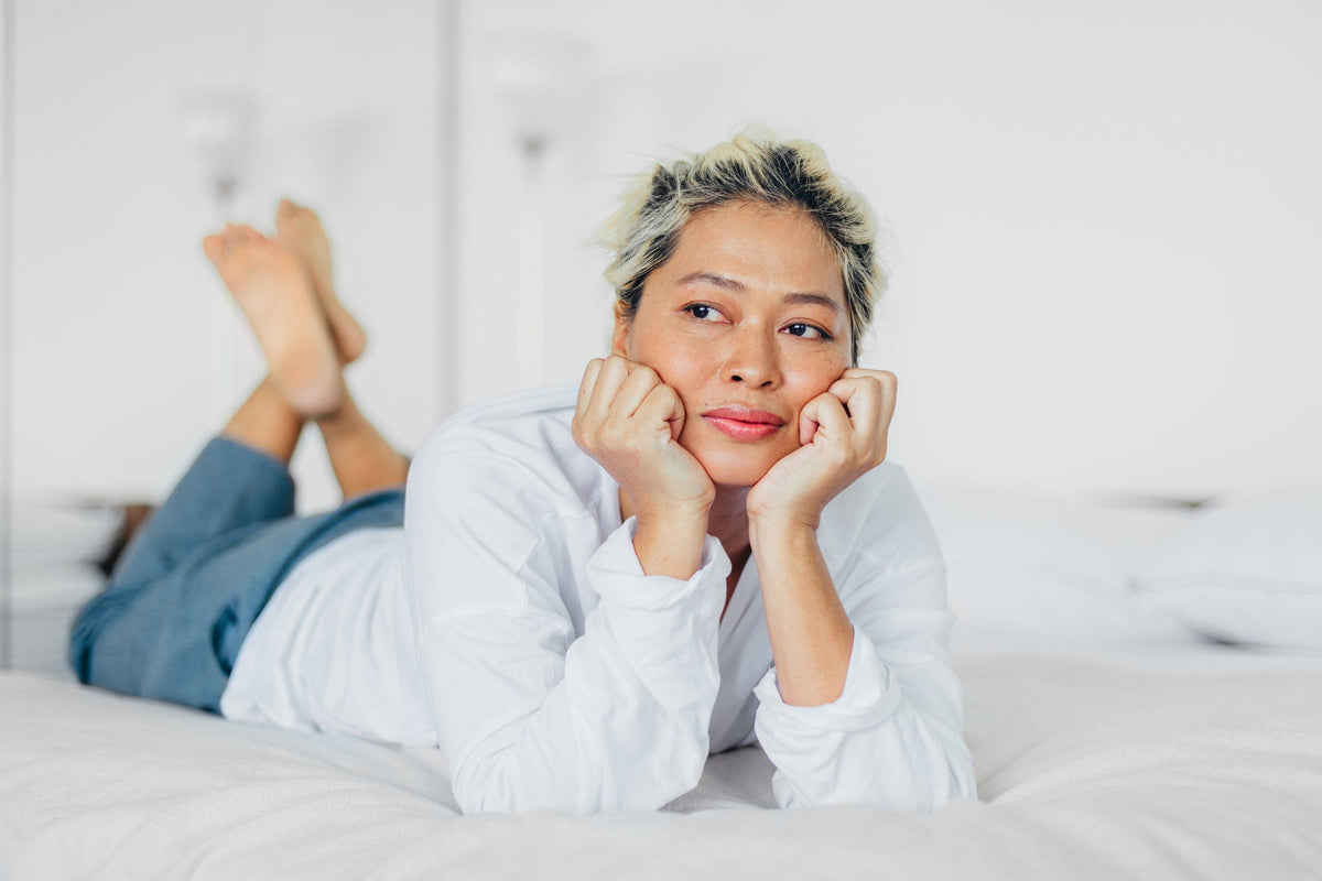 Woman laying on bed in thought