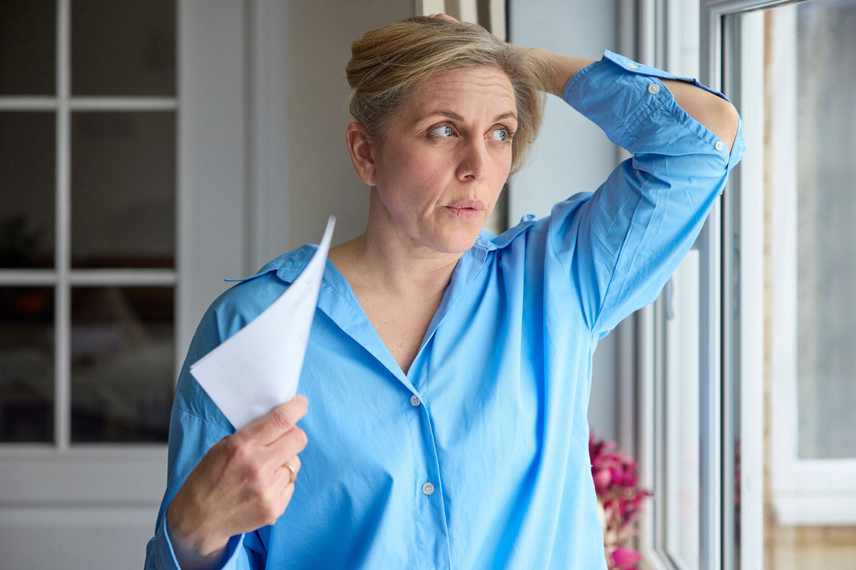 Woman with paper looking out window